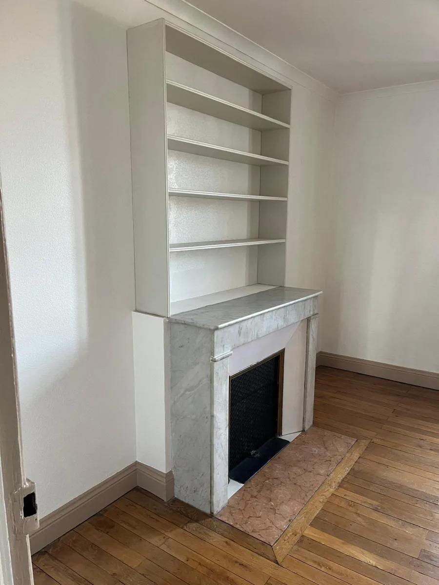 Avant : chambre aux murs blancs avec cheminée en marbre et étagères